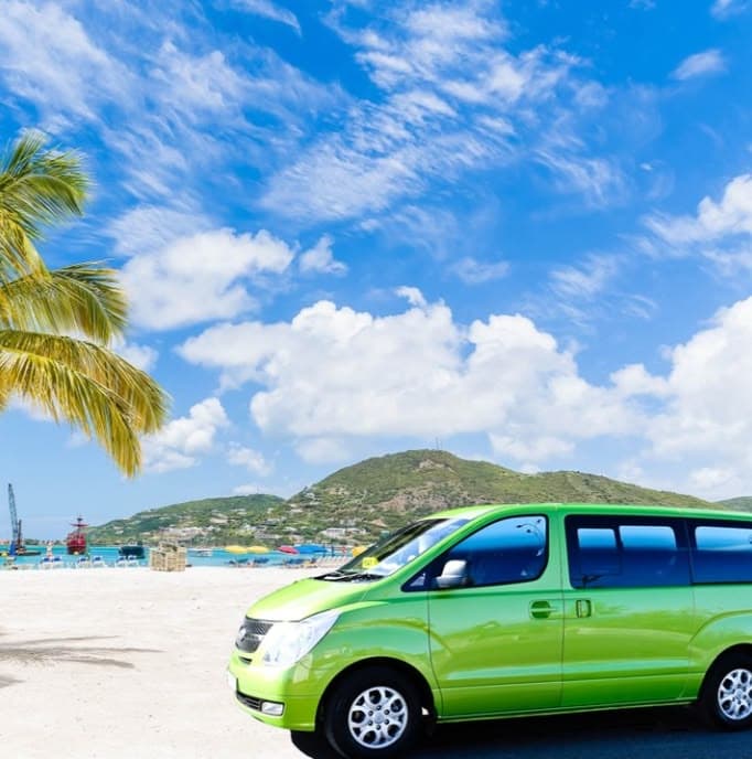 Bright lime green van parked on a white sand beach under a clear blue sky.
